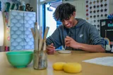 A student smiling at the pottery wheel