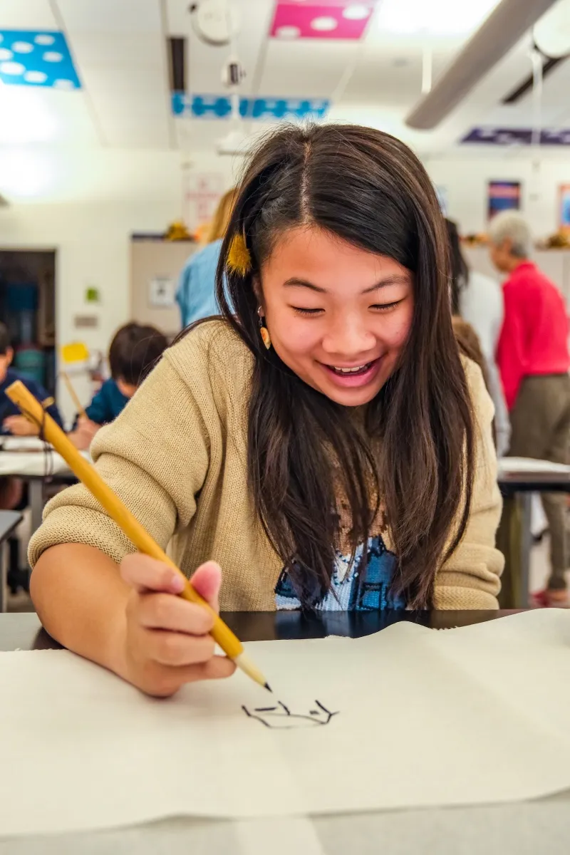 A student in headphones draws at her desk
