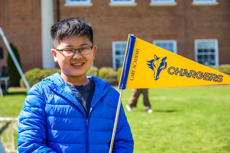 A student holds a Chargers pennant on the quad
