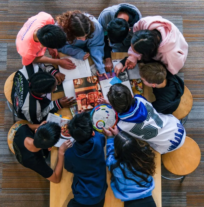 Students talk around a round table, seen from above