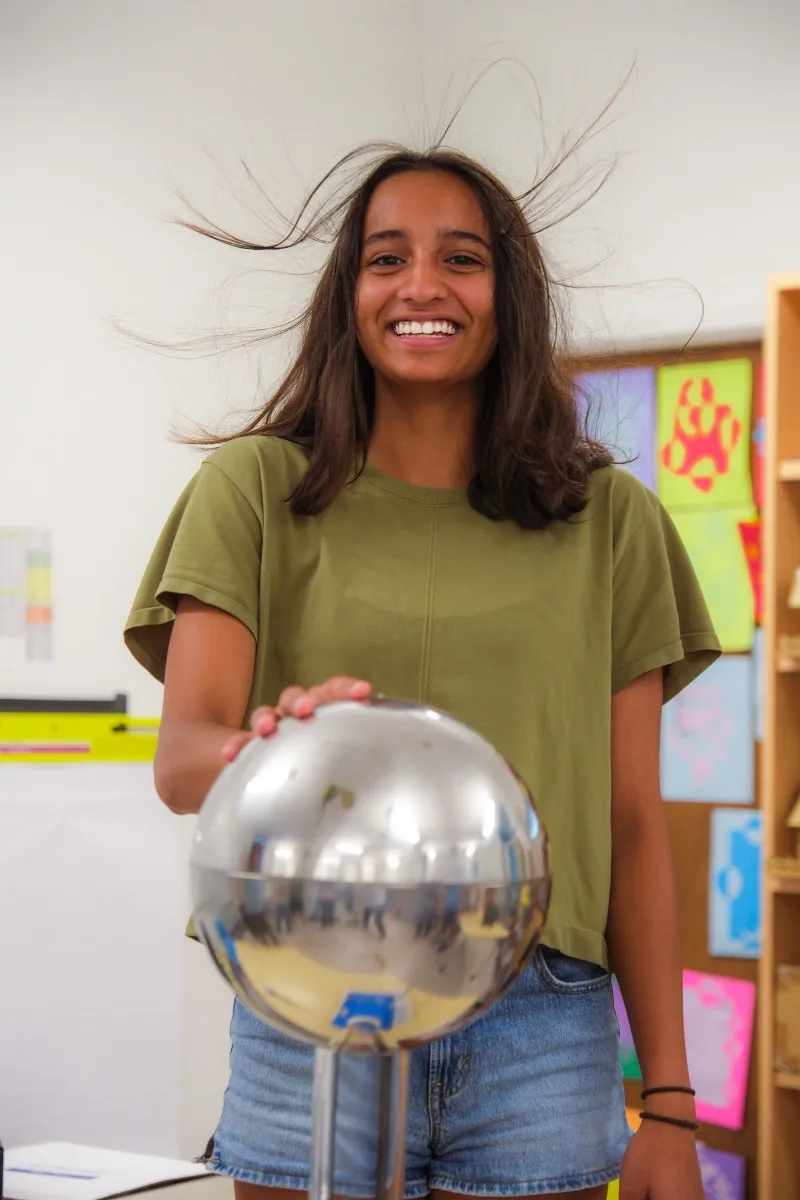 A student laughs as a static generator lifts her hair